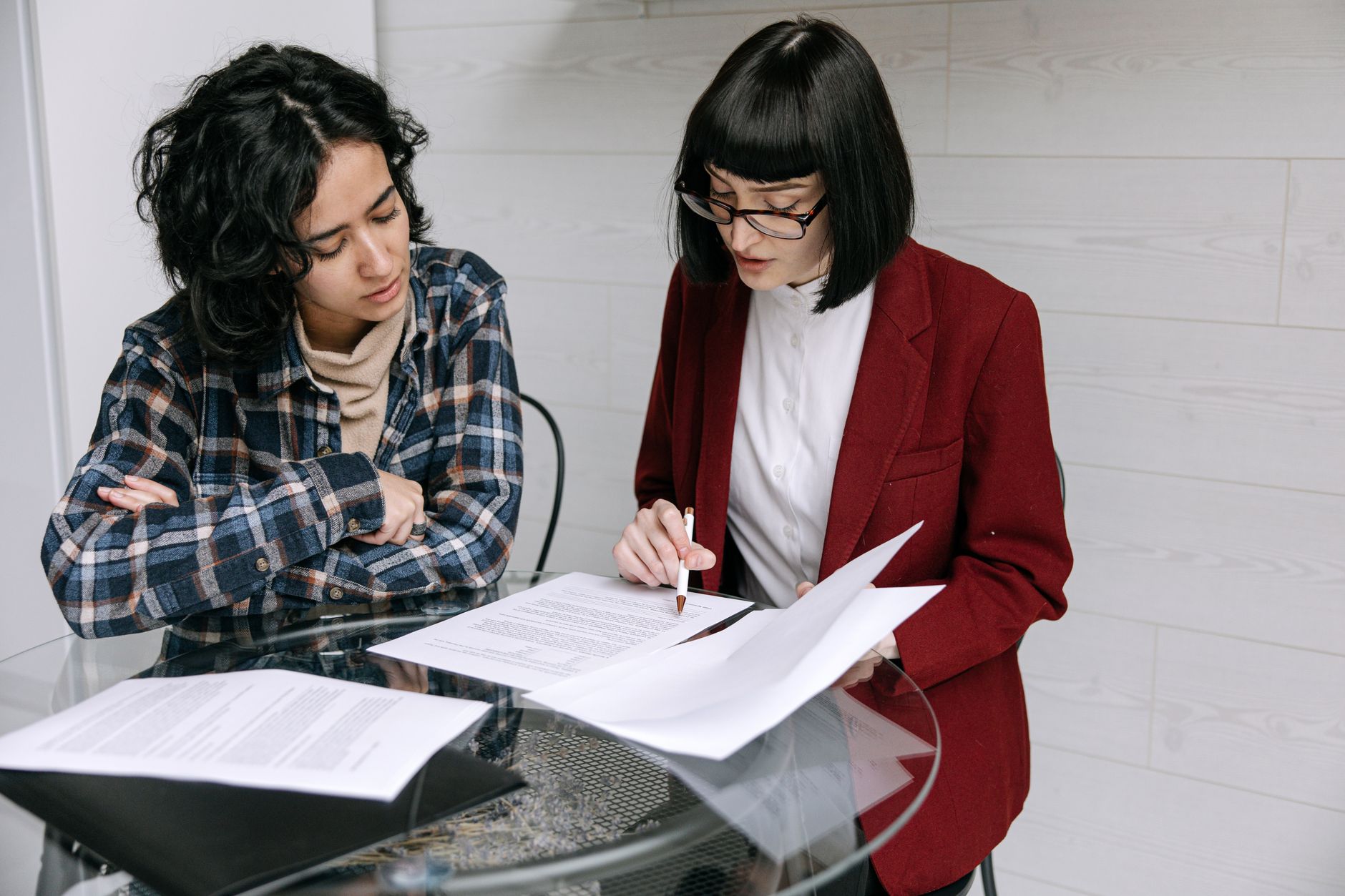 A real estate agent and a loan officer reviewing documents together at a table